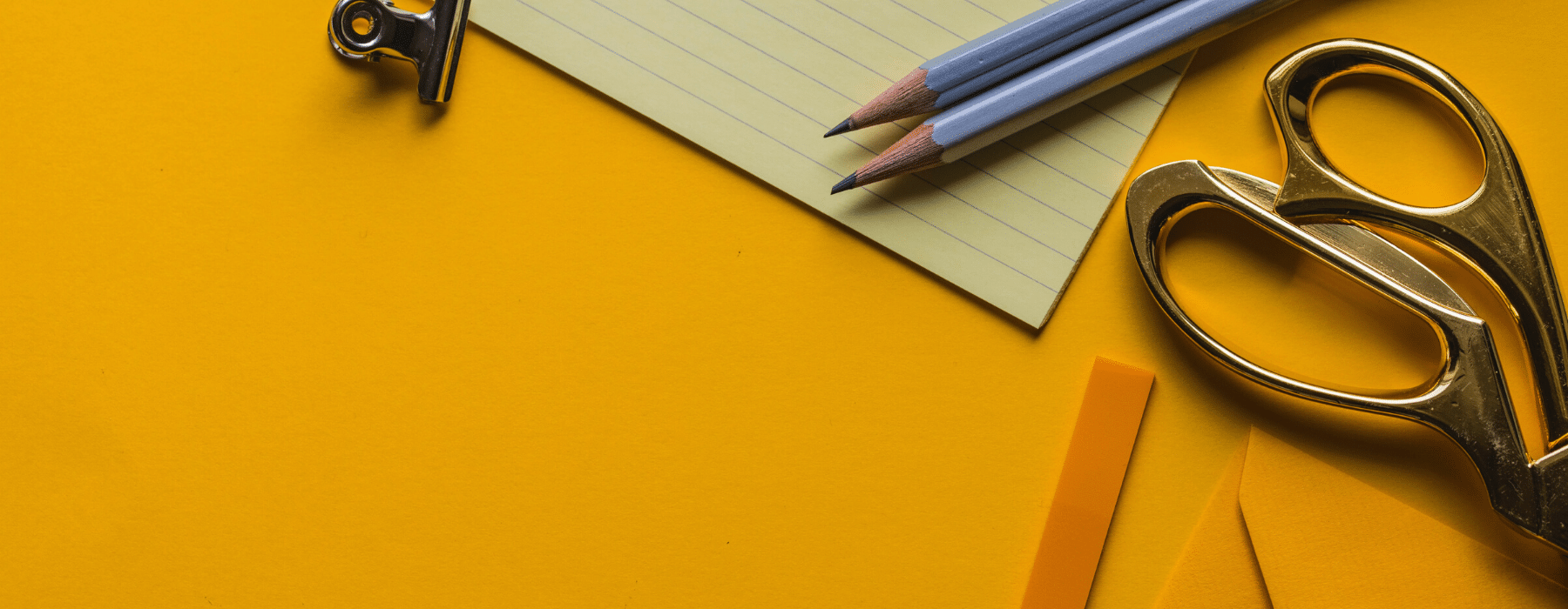 two pencils and scissors in orange background