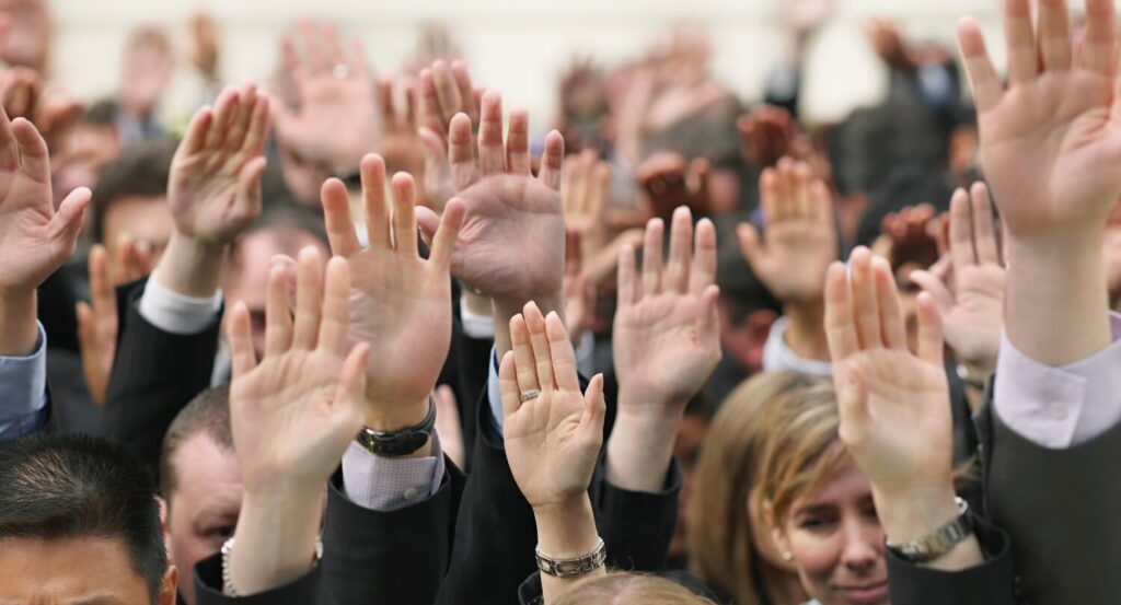 A group of business people raising their hands.