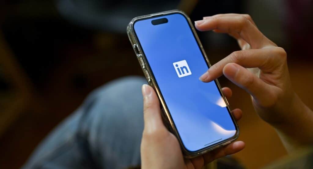 A person holding a smart mobile with the LinkedIn app loading