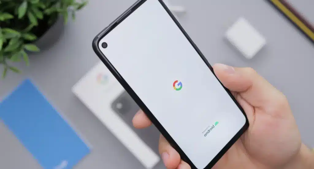 A hand holding an android phone that is loading the google app