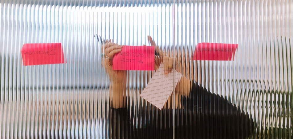 Sticky notes being added to a glass meeting room